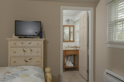 A television on the nightstand with bathroom in the background