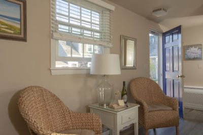 2 wicker chairs and nightstand with lamp and cheese and wine