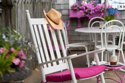 a rocking chair with pink cushion andsunhat