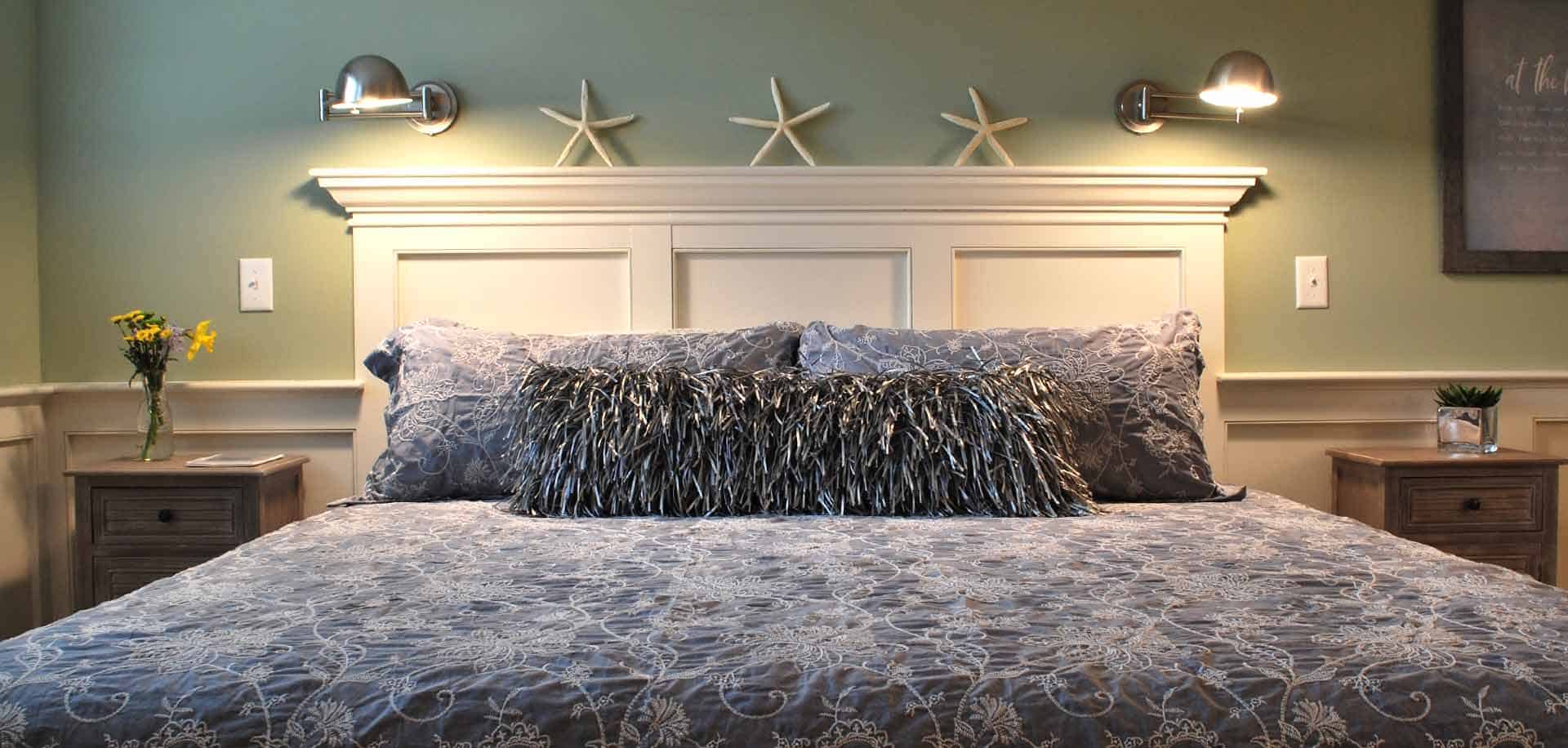 A chic gray bedspread and pillows with starfish decor above the headboard