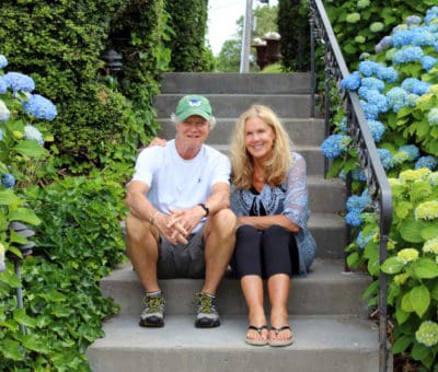 Peter and Denise Butcher sit on steps surrounded by hydrangea flowers