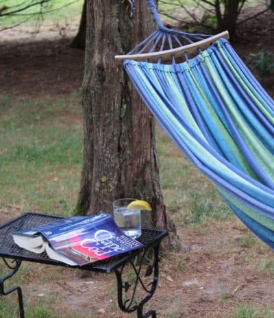 A hammock with a book and glass of water with lemo