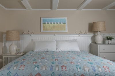Two pillows on the bed with white headboard and nautical duvet including pictures of beach shanties